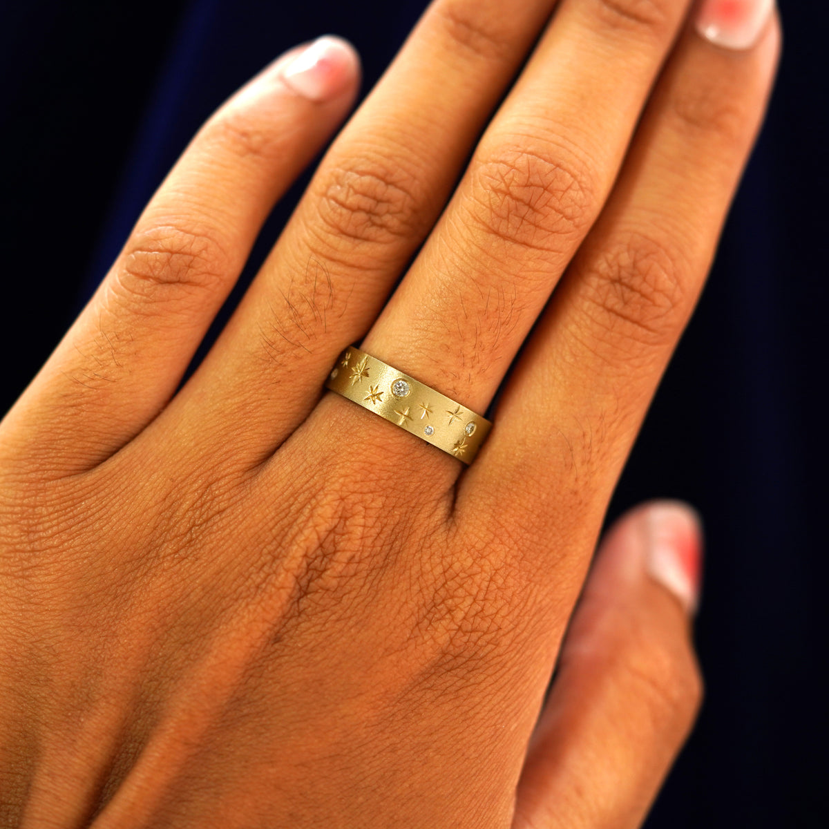 Close up view of a model's hand wearing a yellow gold Stars and Diamonds Band