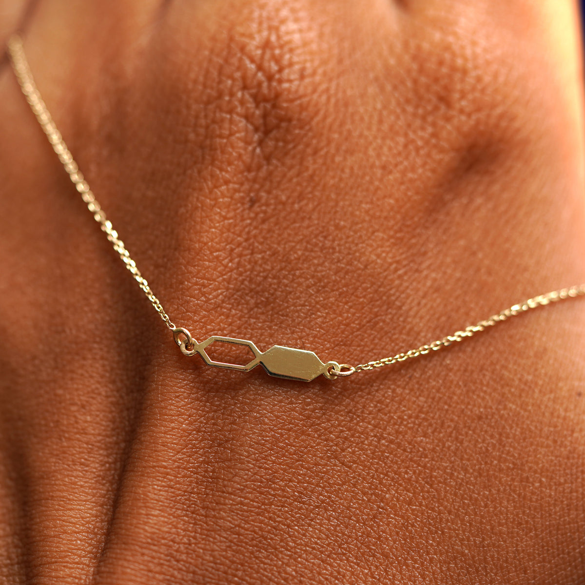 A solid gold Tanlah Cable Bracelet resting on the back of a model's hand