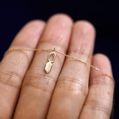 A yellow gold Tanlah Cable Necklace resting on a model's fingers