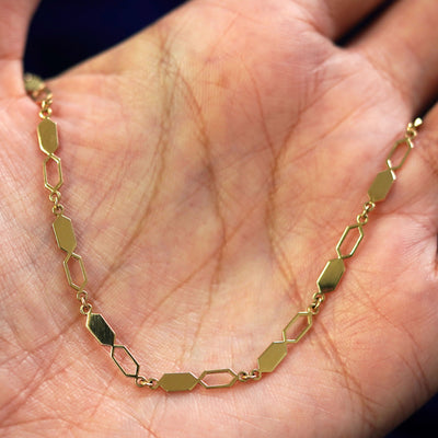 A yellow gold Tanlah Bracelet draped on a model's palm
