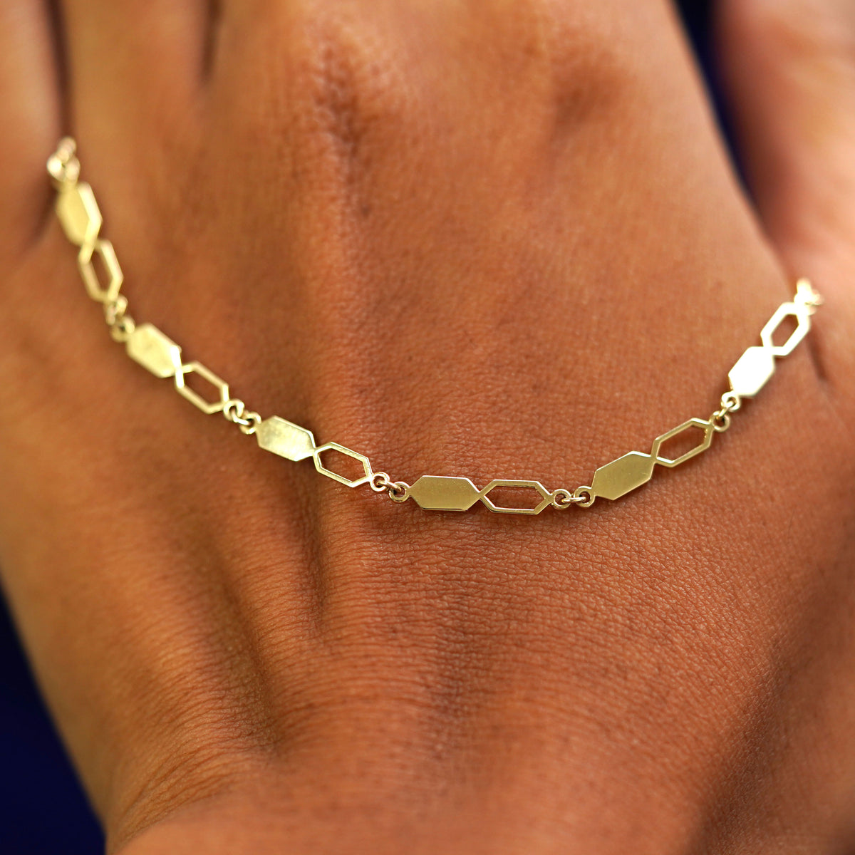 A solid gold Tanlah Bracelet resting on the back of a model's hand
