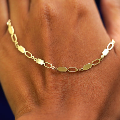 A solid gold Tanlah Bracelet resting on the back of a model's hand