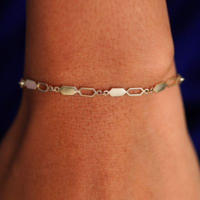 Close up view of a model's wrist wearing a solid yellow gold Tanlah Bracelet