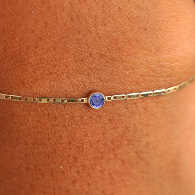 Close up view of a models wrist wearing 14k yellow gold Tanzanite Bracelet