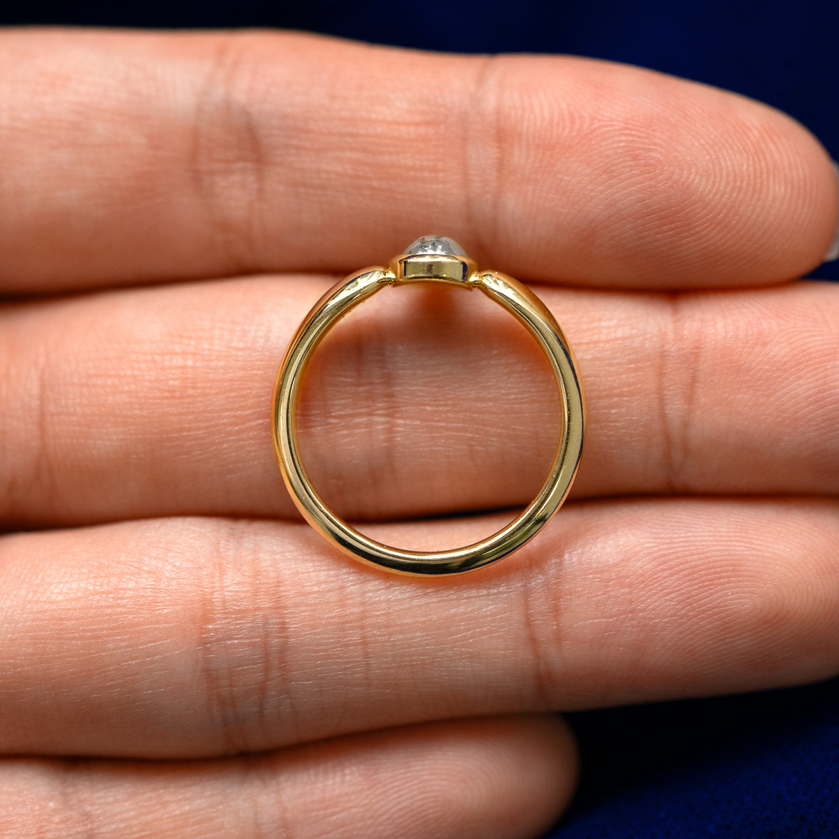 A yellow gold pear salt and pepper diamond cabochon teardrop ring in a model's hand showing the thickness of the band