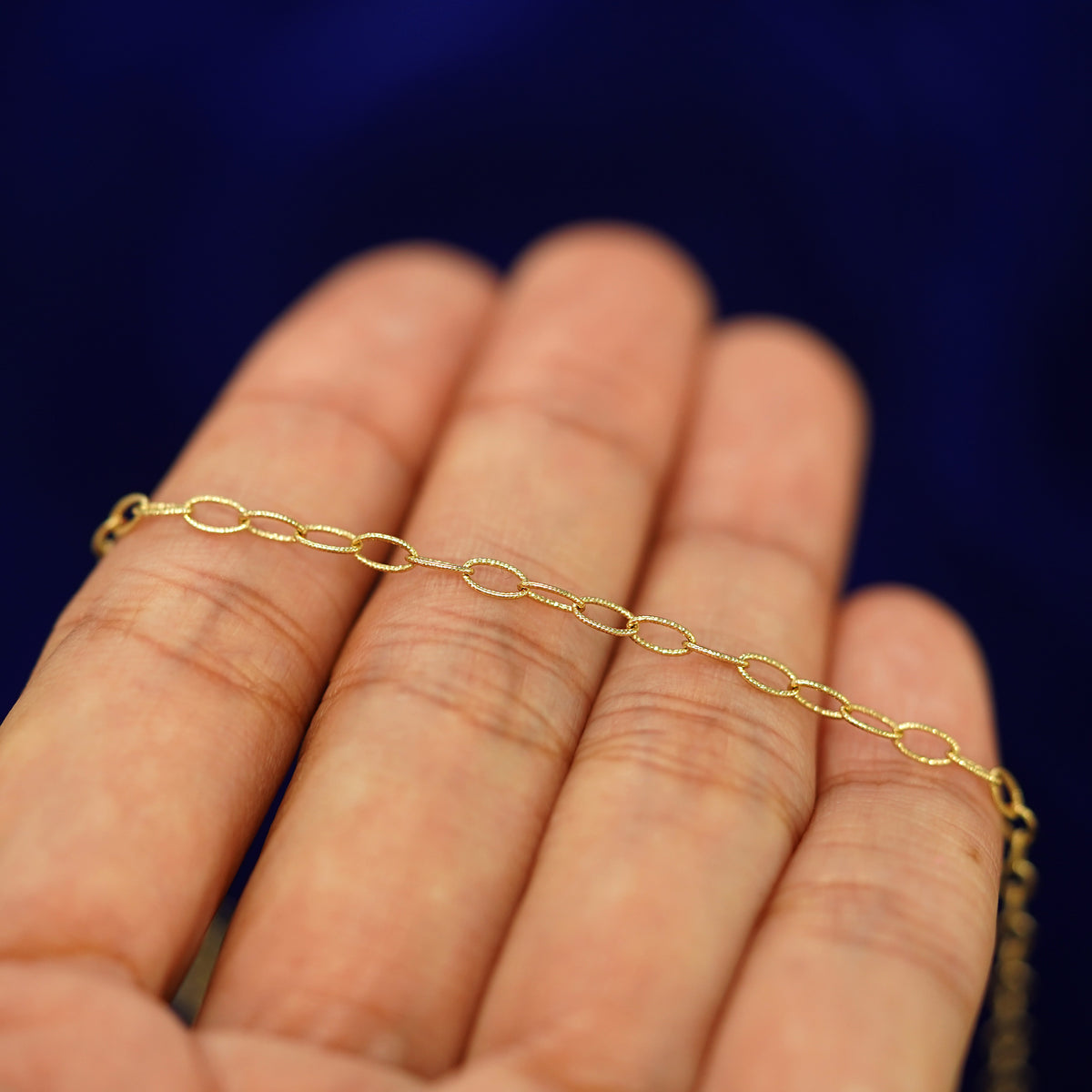 A yellow gold Veren Bracelet resting on a model's fingers
