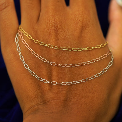 Three versions of the Veren Chain showing options of yellow, white, and rose gold resting on the back of a model's hand