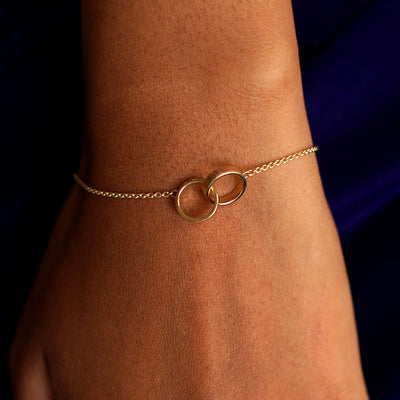 Close up view of a model's wrist wearing a solid yellow gold Bound Together Bracelet