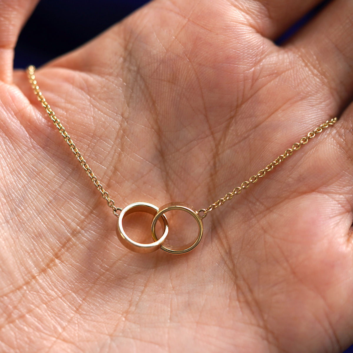 A yellow gold Bound Together Bracelet draped on a model's palm