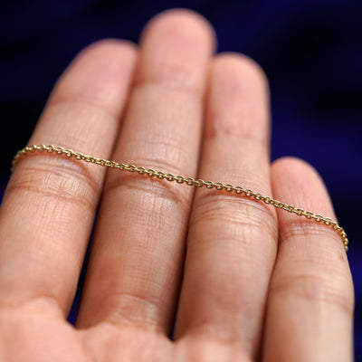A yellow gold Thick Cable Anklet resting on a model's fingers
