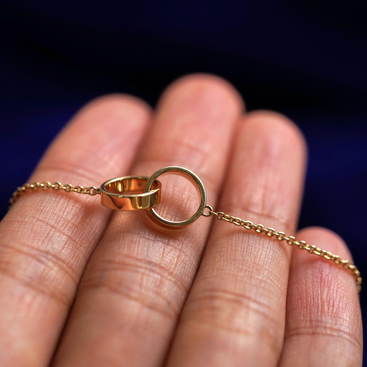 A yellow gold Bound Together Bracelet resting on a model's fingers