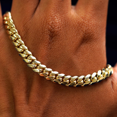 A solid gold Miami Cuban Anklet resting on the back of a model's hand