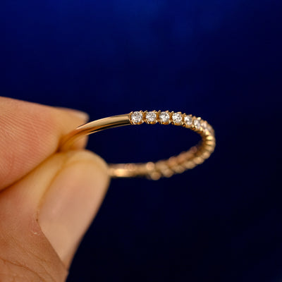 A model holding a Mini Petal Set Diamond Eternity Band up to show the details of the design and the inside of the ring