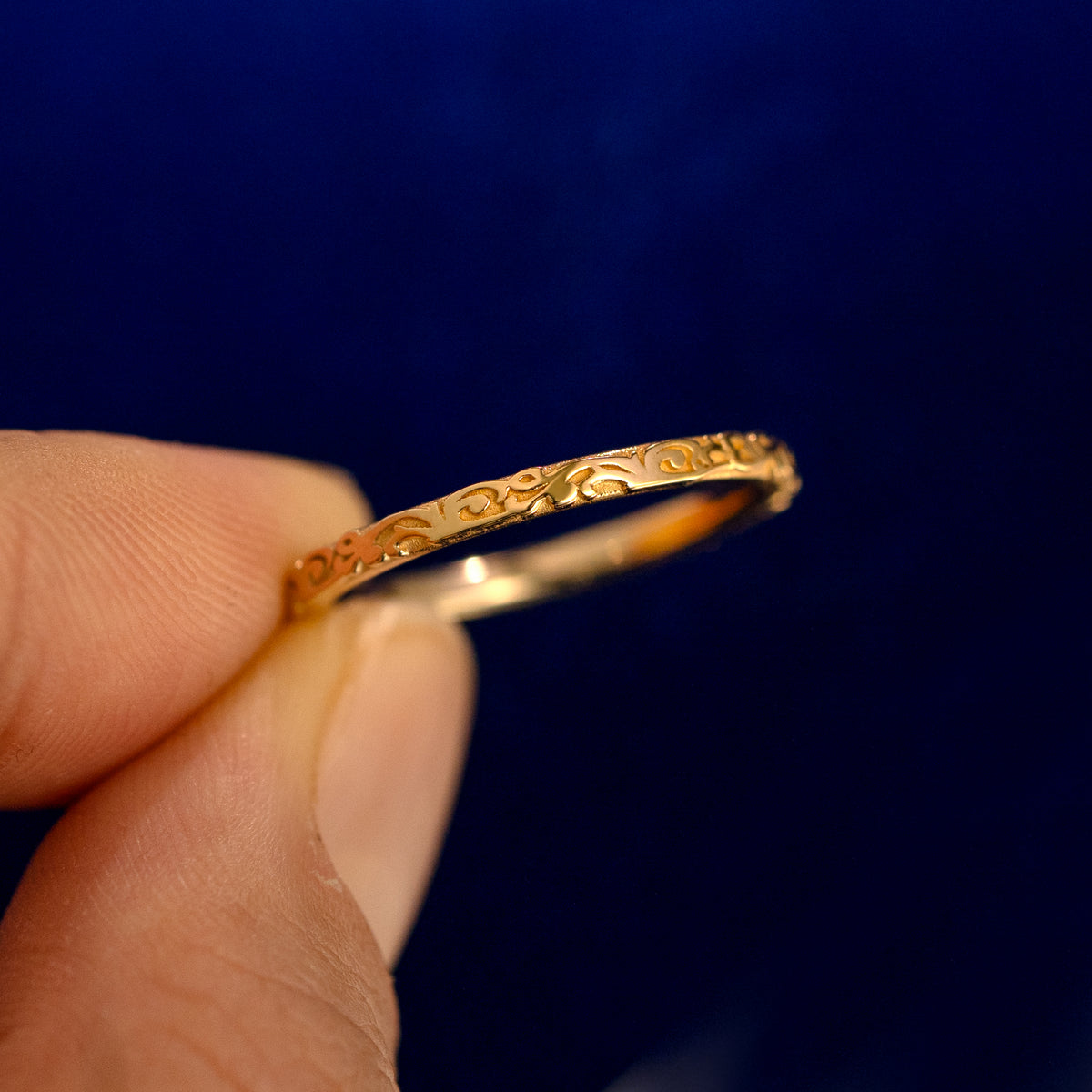 A model holding a Thin Filigree Band up to show the details of the design and the inside of the ring