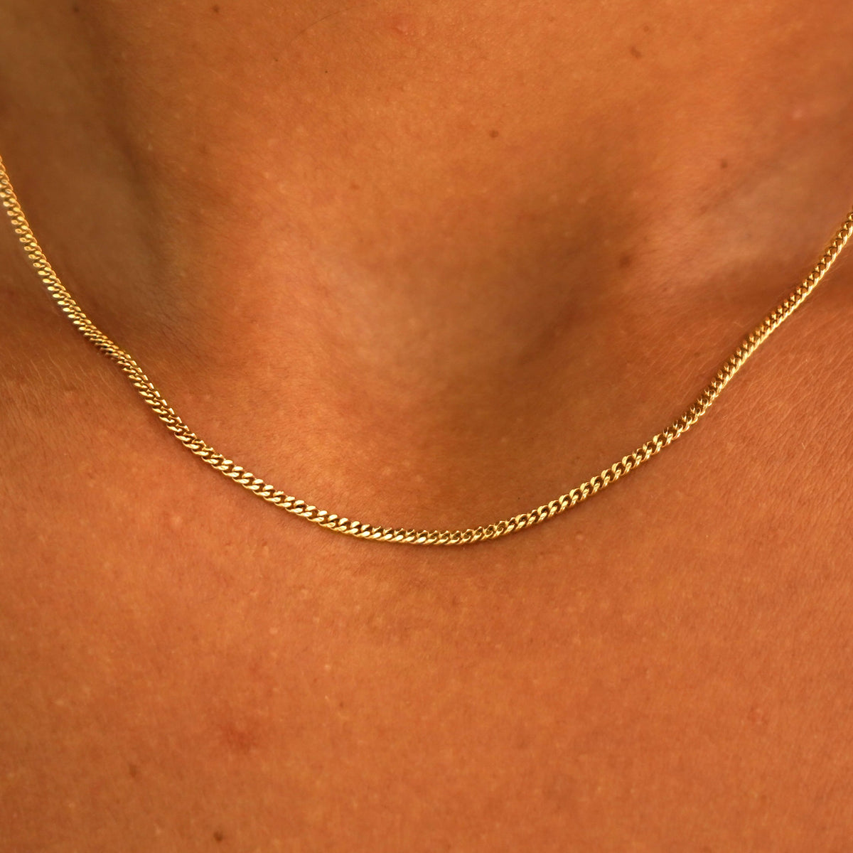 Close up view of a model's neck wearing a solid yellow gold Mini Miami Chain