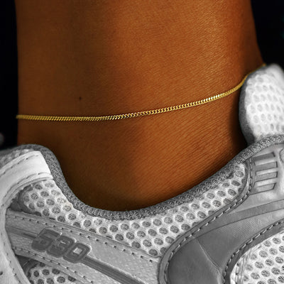 A model's ankle wearing a solid yellow gold Mini Miami Anklet
