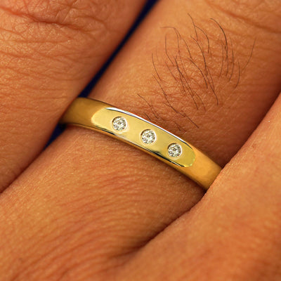 Close up view of a model's fingers wearing a 14k yellow gold Mix Mirror Band with three diamonds