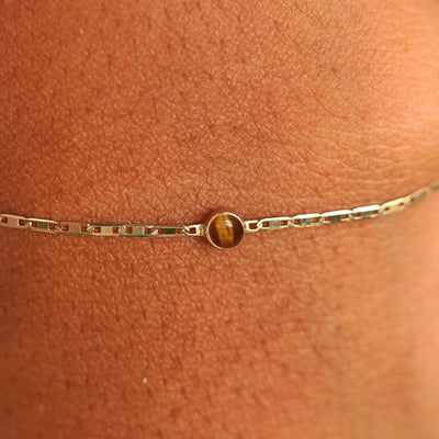 Close up view of a models wrist wearing 14k yellow gold Tiger Eye Bracelet