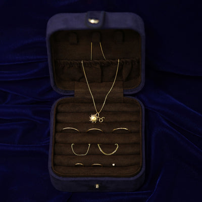 An open Automic Gold Travel Case  with multiple pieces of solid gold jewelry inside and a necklace half in the pouch on top