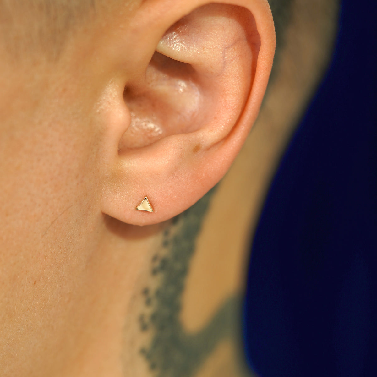 A model's ear wearing a 14k yellow gold Triangle Earring