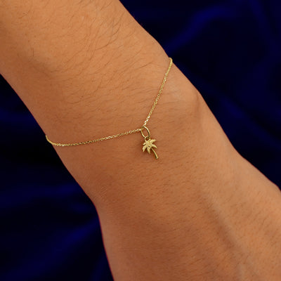 A model's wrist wearing a yellow gold Palm Tree Charm on a Cable Bracelet