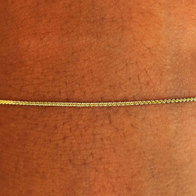 Close up view of a model's wrist wearing a solid 14k yellow gold Wheat Chain