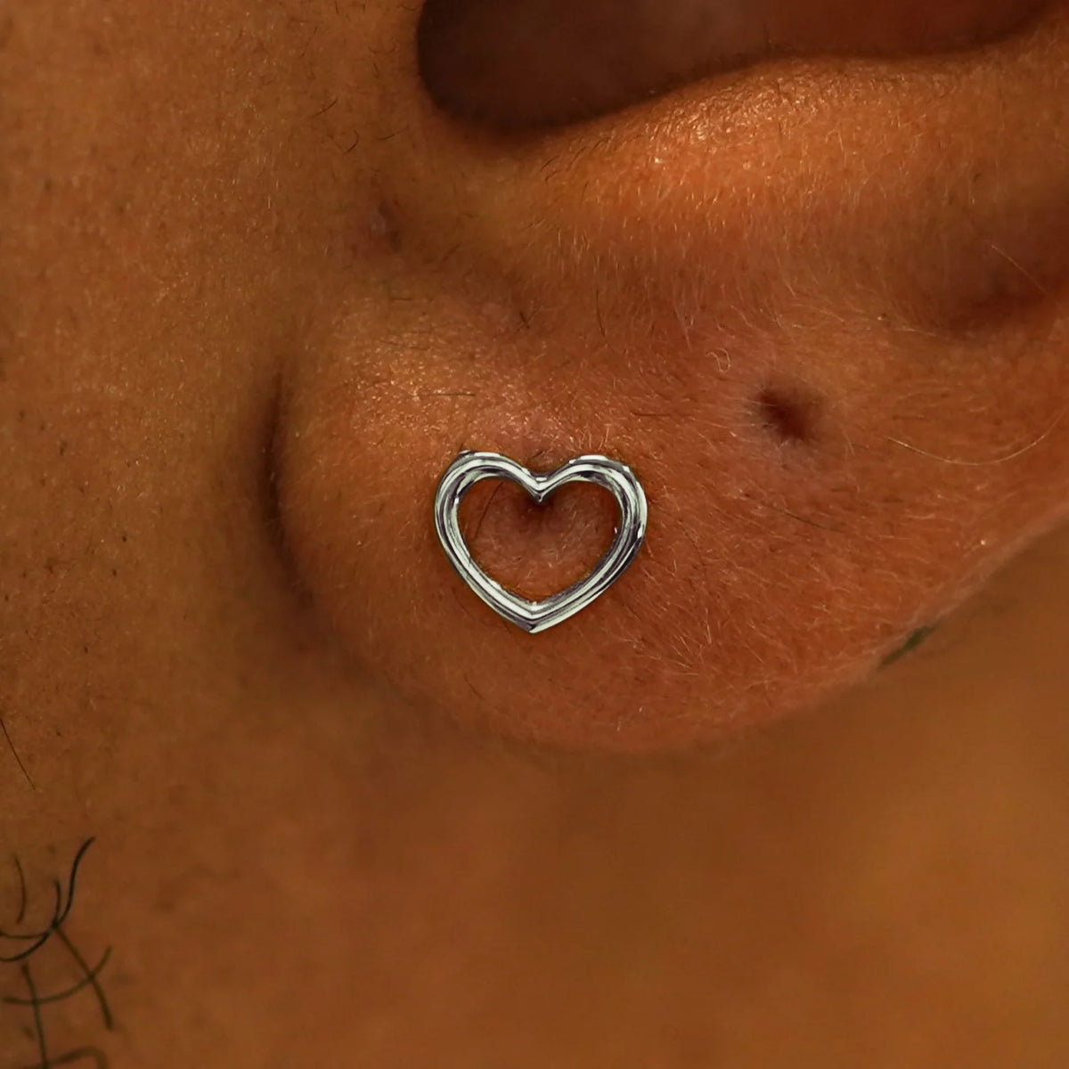 Close up view of a model's ear wearing a 14k white gold Heart Earring