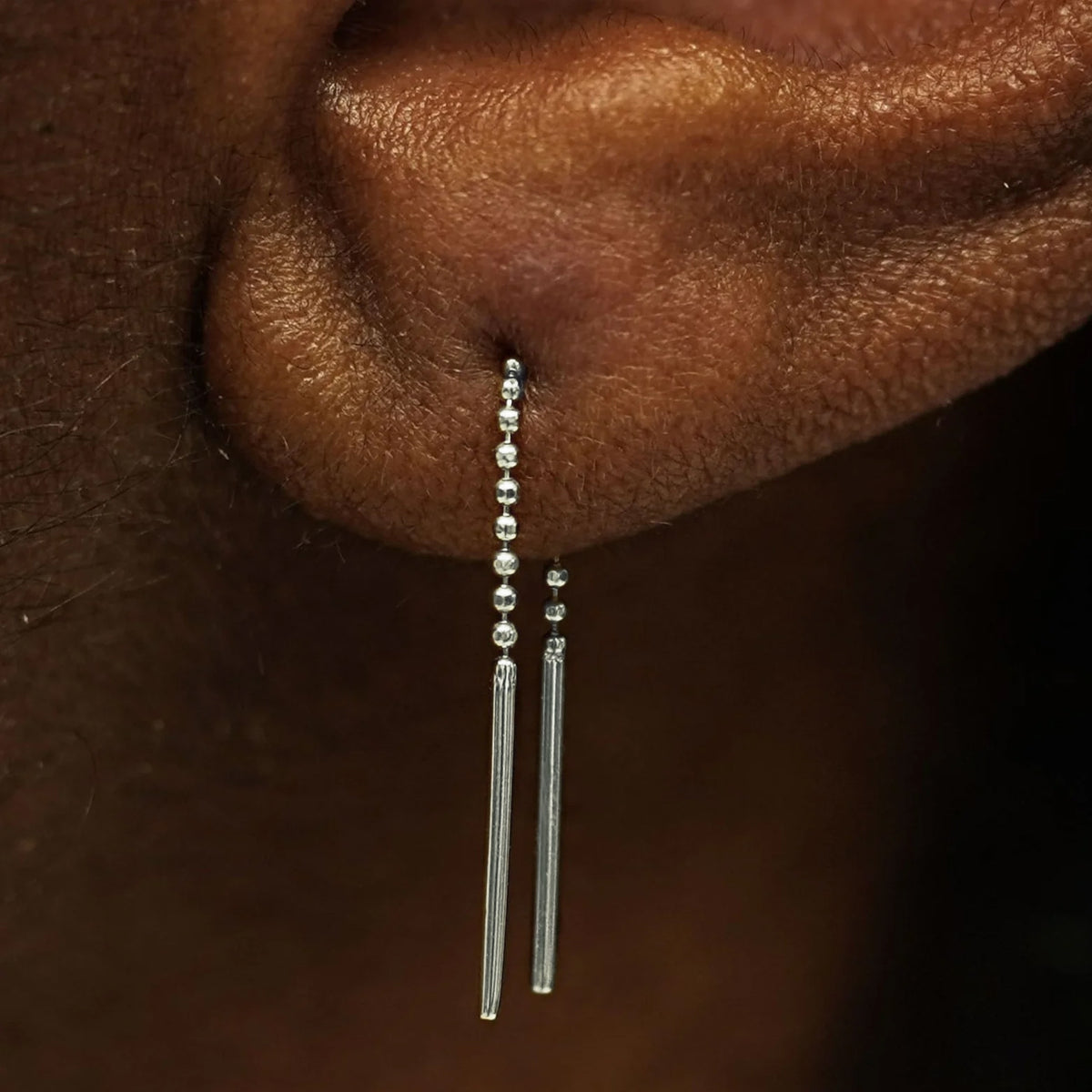 Close up view of a model's ear wearing a solid 14k white gold Mini Threader