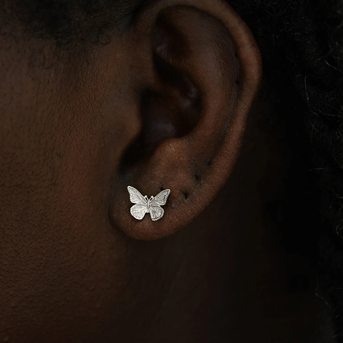 Close up view of a model's ear wearing a 14k white gold Butterfly Earring