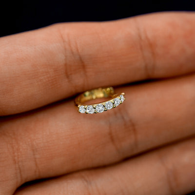 A small White Lab Diamond huggie hoop earring between a model's fingers to show the gems