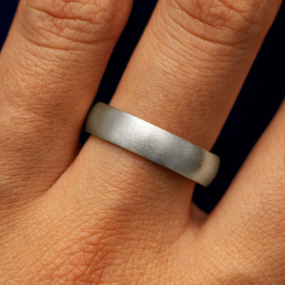 A models hand wearing a 14k white gold curvy matte band
