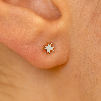 Close up view of a models ear wearing a 14k white gold 8 pointed star flatback piercing