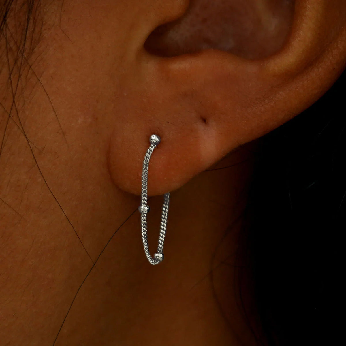 Close up view of a model's ear wearing a white gold Beaded Chain Loop Earring