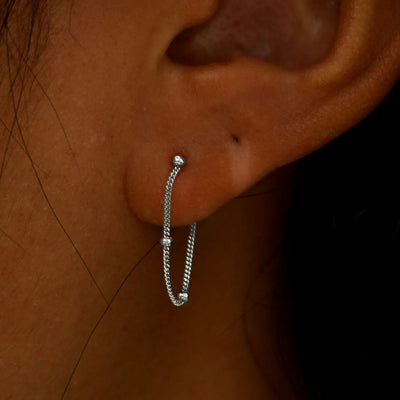 Close up view of a model's ear wearing a white gold Beaded Chain Loop Earring