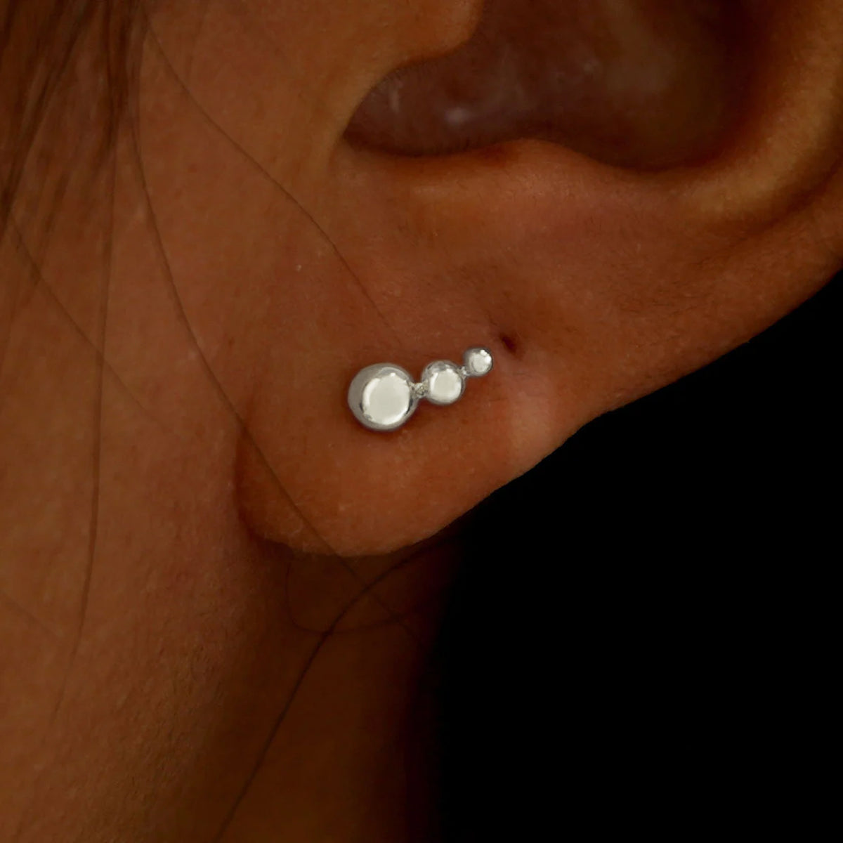 A model's ear wearing a solid white gold Graduated Ball Earring