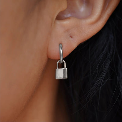 A 14 karat solid white gold Lock Charm resting on the back of a model's hand