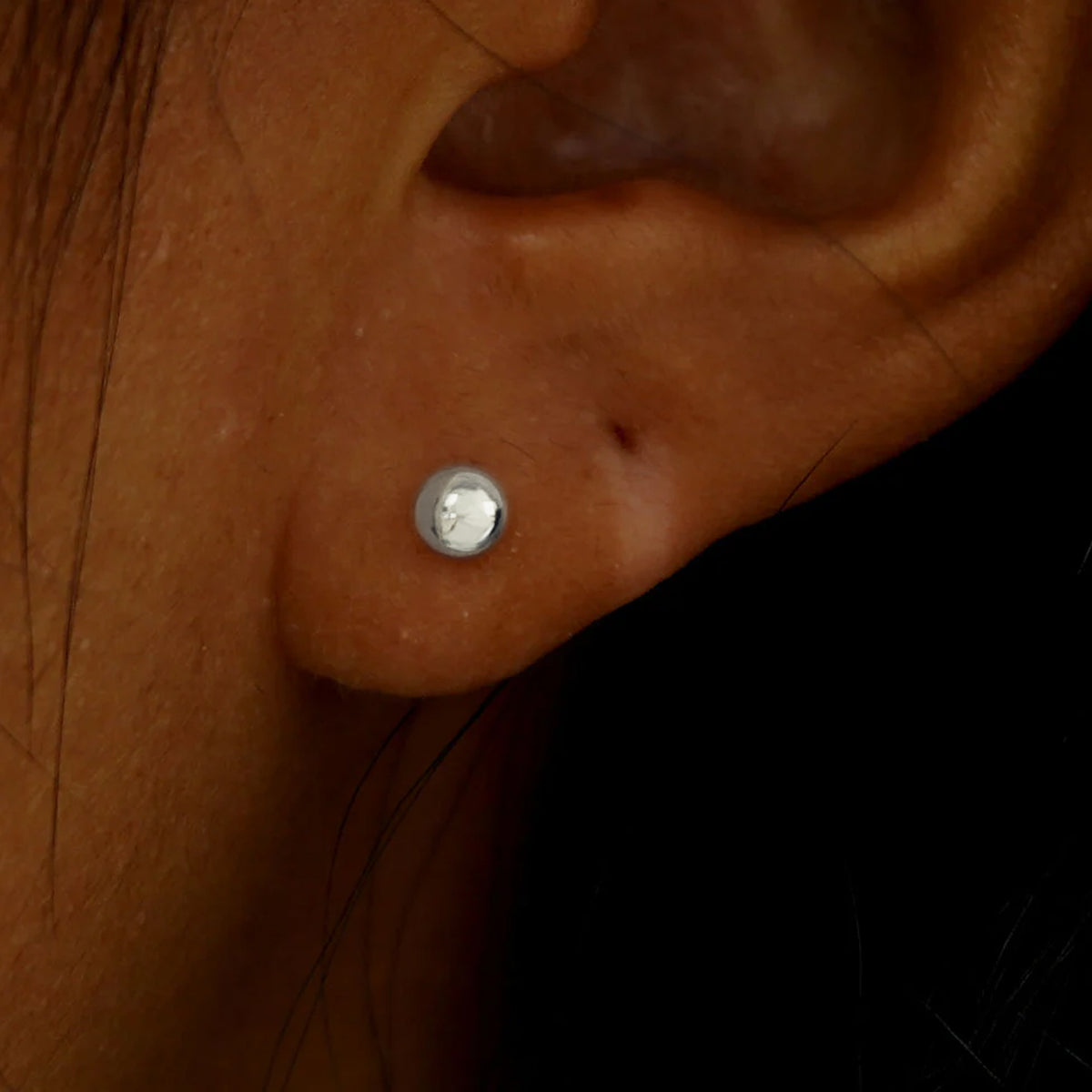 A model's ear wearing a solid white gold Medium Ball Earring