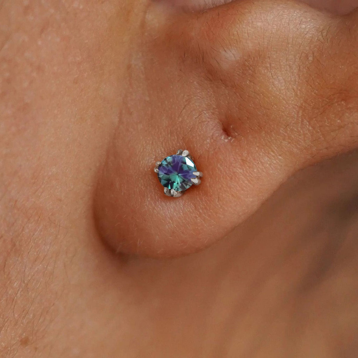 Close up view of a model's ear wearing a 14k white gold Alexandrite Stud Earring