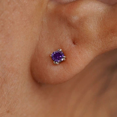 Close up view of a model's ear wearing a 14k white gold Amethyst Stud Earring