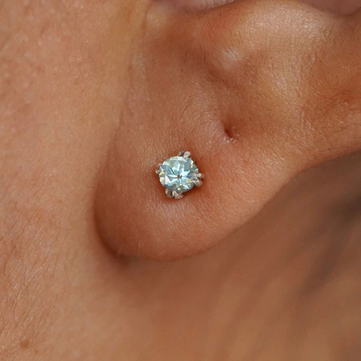 Close up view of a model's ear wearing a 14k white gold Aquamarine Earring