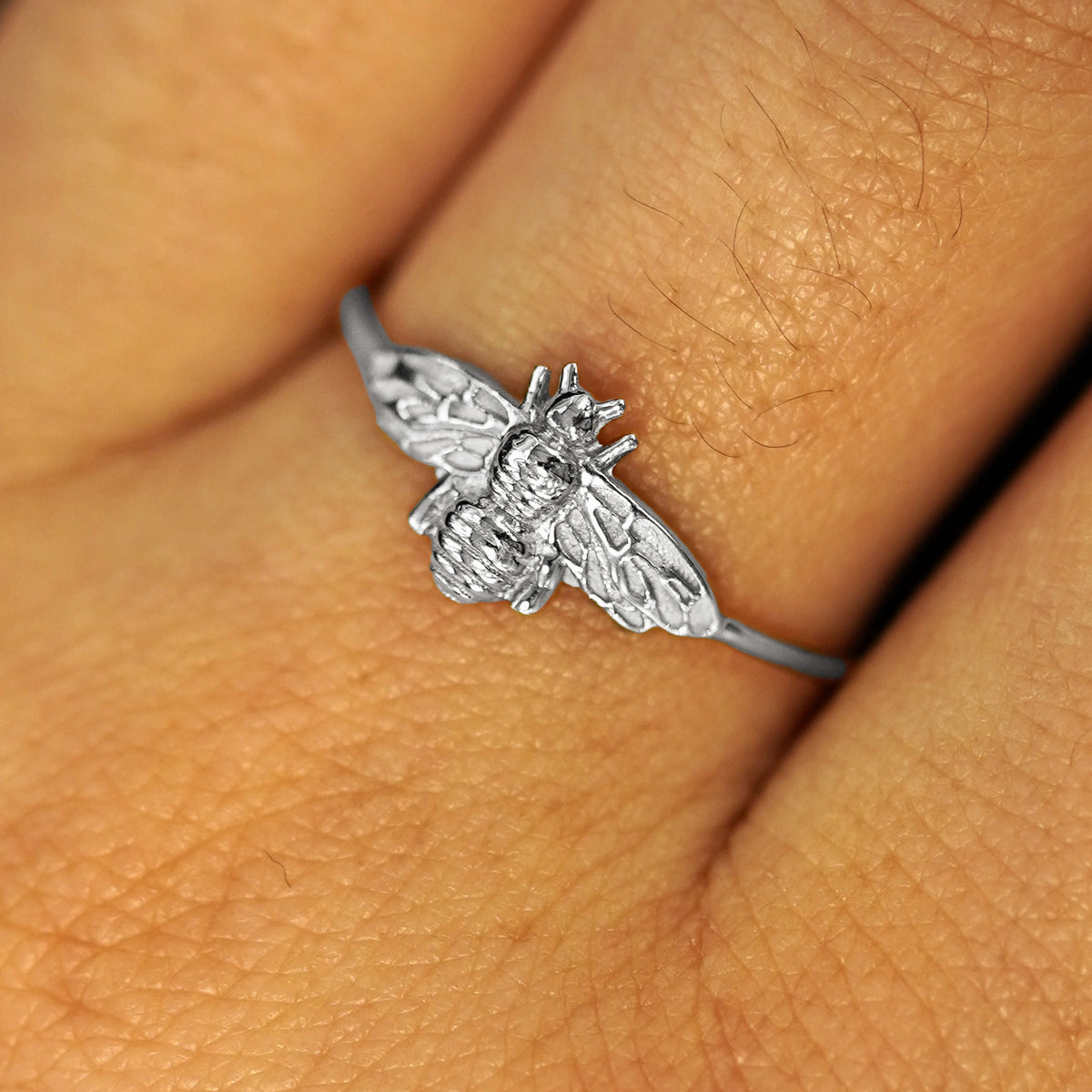 Close up view of a model's fingers wearing a solid white gold Bee Ring