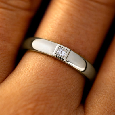 Close up view of a model's fingers wearing a 14k white gold Square Carre Cut Diamond Band