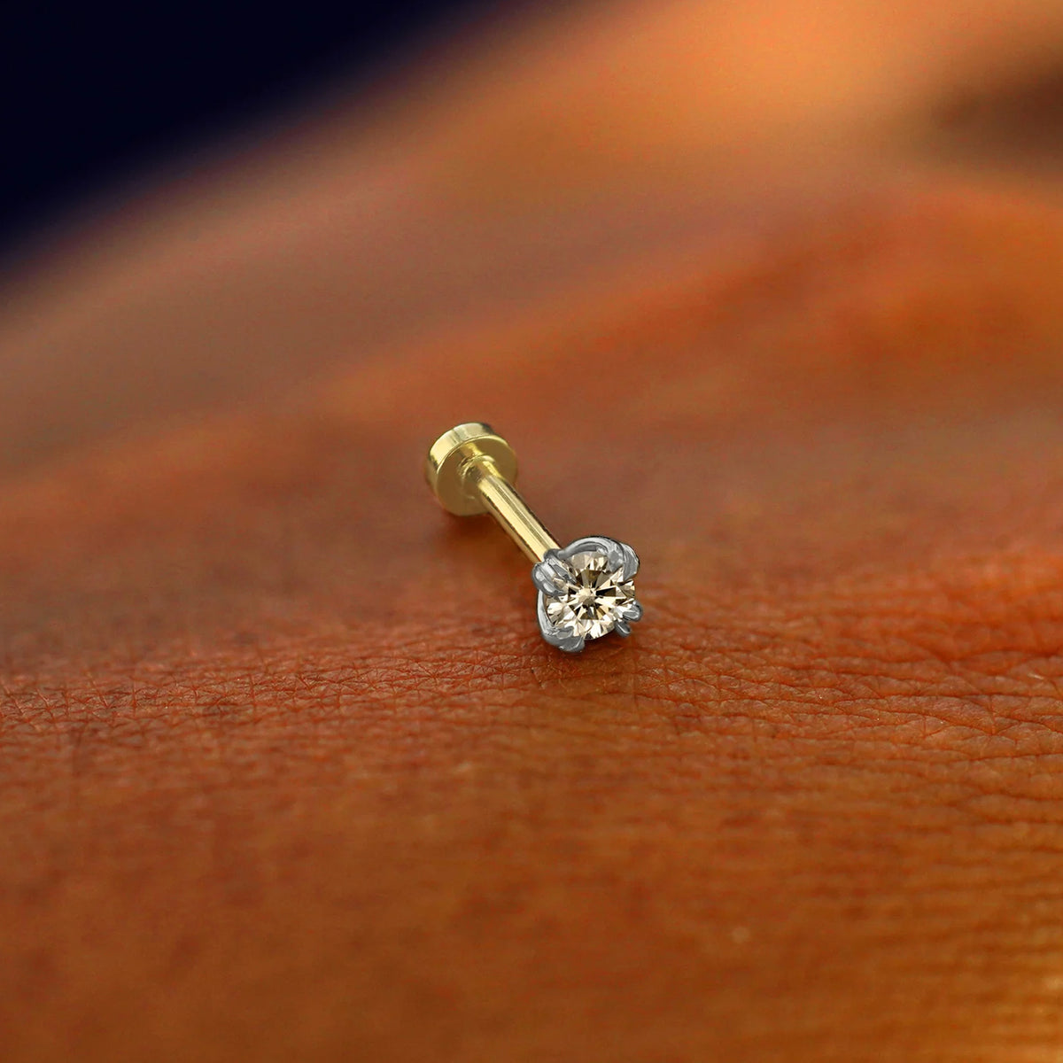 A solid 14k white gold Champagne Diamond Flatback Piercing resting on the back of a model's hand