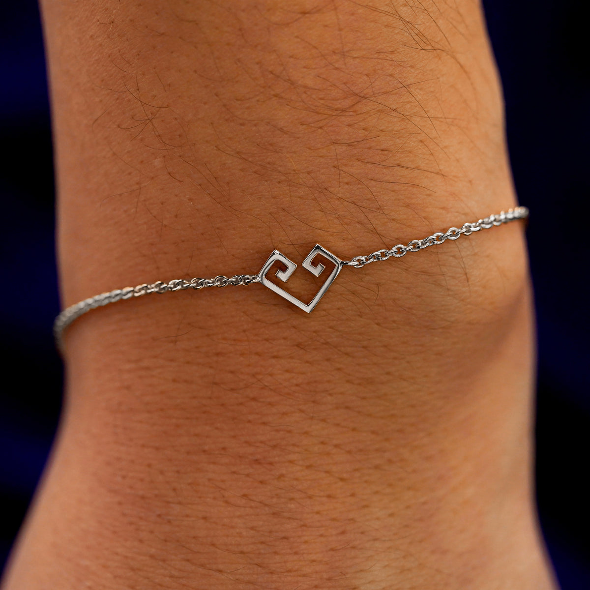 A close up view of a model's wrist wearing a white gold Chere Heart Bracelet