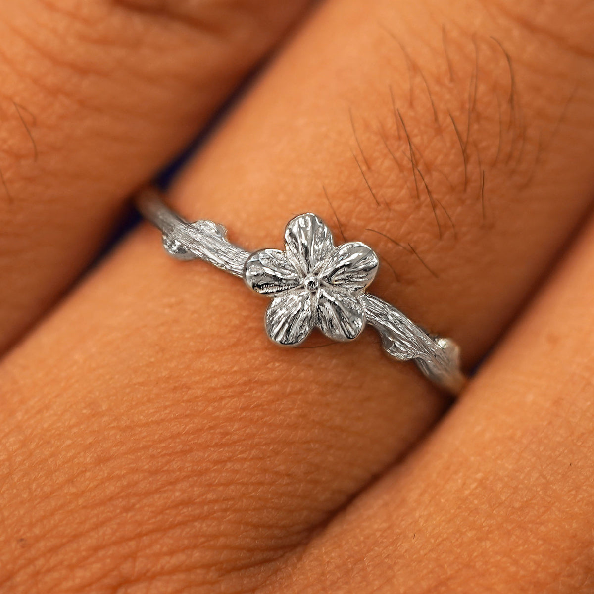 Close up view of a model's fingers wearing a white gold Sakura Ring