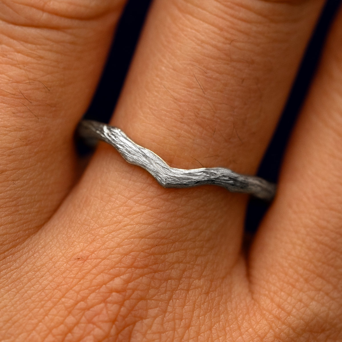Close up view of a model's fingers wearing a 14k white gold Chevron Branches Band