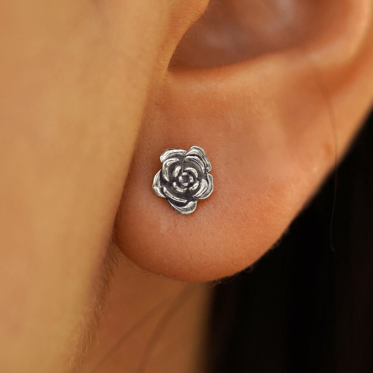 Close up view of a model's ear wearing a 14k white gold Rose Earring