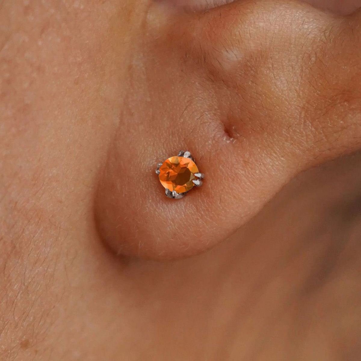 Close up view of a model's ear wearing a 14k white gold Moissanite Stud Earring