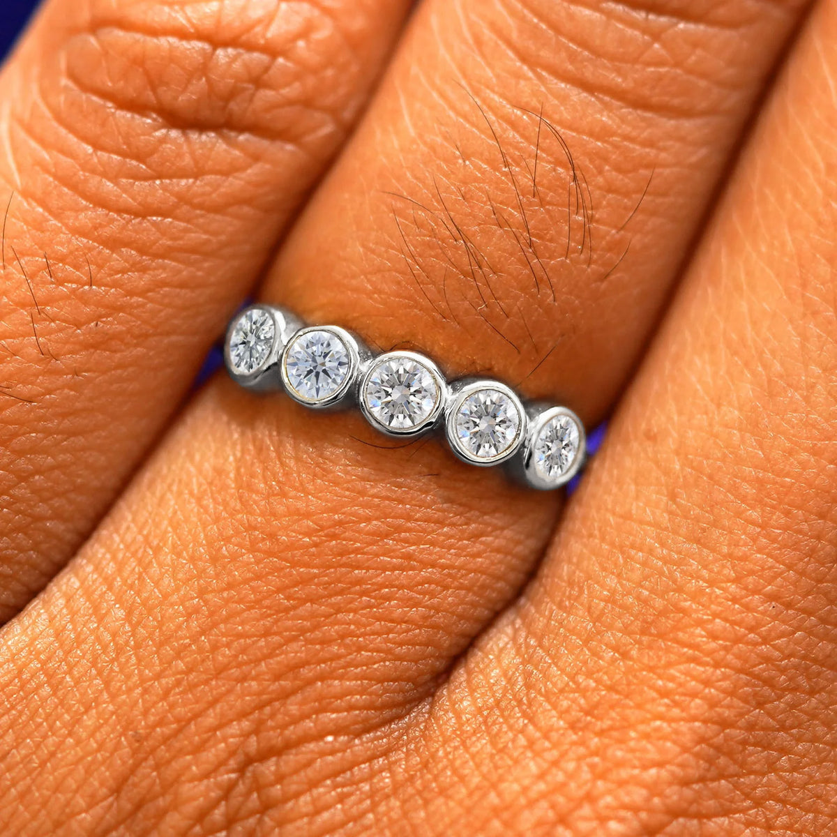 Close up view of a model's fingers wearing a 14k white gold Five Diamond Ring with clear diamonds