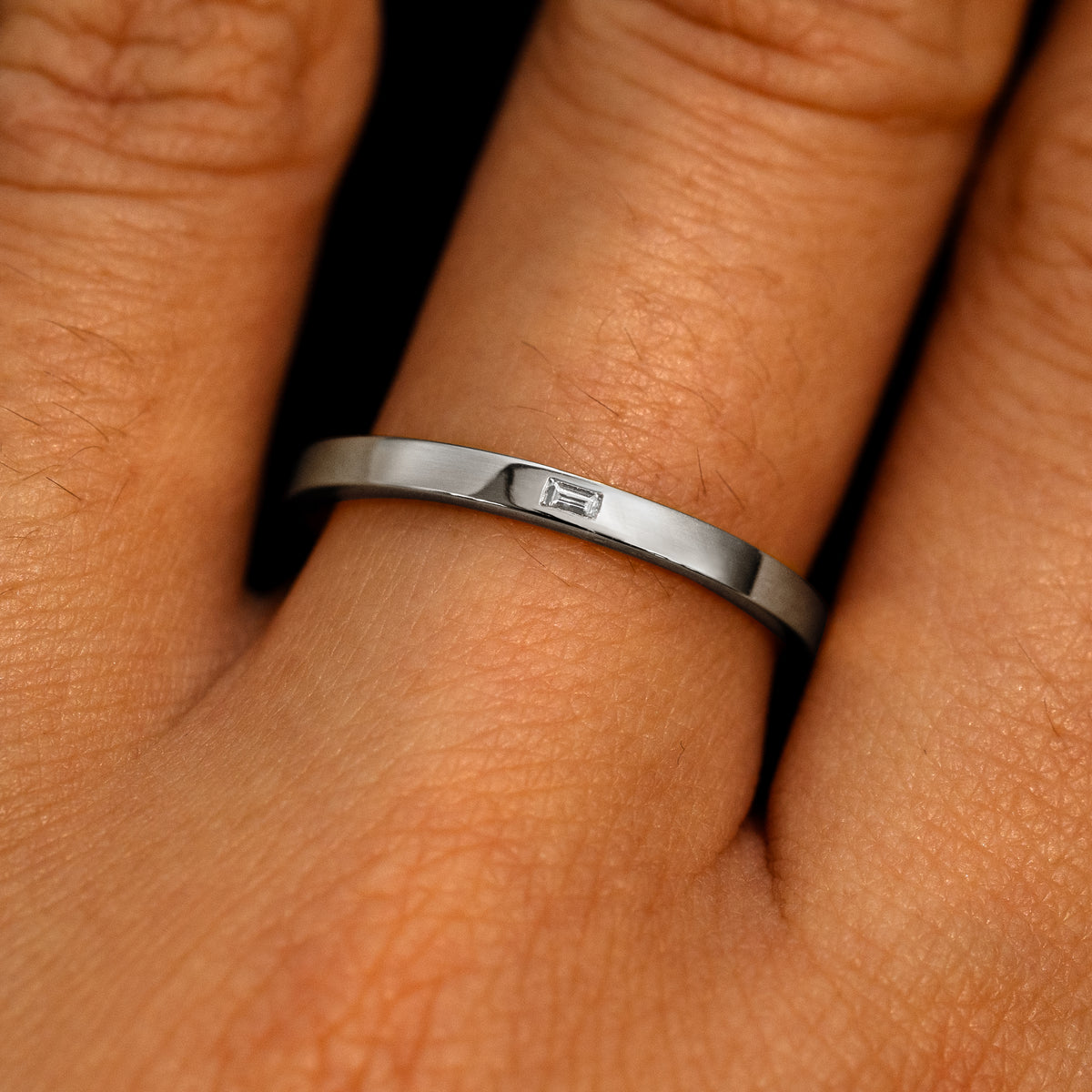 A 14k white gold Flush Set Baguette Diamond Ring on a model's finger